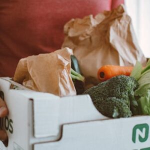 Person holding a box filled with fresh vegetables, ideal for health and produce concepts.